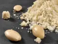 Montón de harina de almendras y almendras enteras. Aprende como hacer harina de almendras casera.