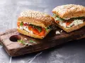 Dos sándwiches de salmón y queso fresco en pan integral, perfectos para un menú de ayuno intermitente.