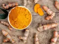 Raíces de cúrcuma y polvo dorado en un cuenco. Descubre qué es la cúrcuma y para qué sirve, un tesoro natural.