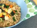 Un tazón de quinoa con pollo y verduras salteadas, como calabacín y zanahoria.