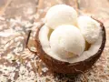 Delicioso helado con leche de coco servido en una cáscara de coco, espolvoreado con coco rallado sobre una mesa de madera.