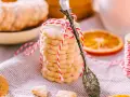 Deliciosas galletas de naranja, apiladas y atadas con hilo rojo y blanco. Una rodaja de naranja y una cuchara antigua completan la escena.