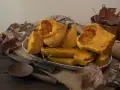 Trozos de calabaza asada, tierna y dorada, servidos en un plato blanco sobre arpillera. Acompañada de utensilios rústicos y hojas secas, evoca el sabor del otoño.