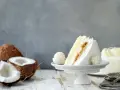 Deliciosa tarta de coco, ideal para tus recetas con harina de coco. Un trozo cremoso con coco rallado y un bombón a juego.