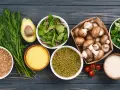 Variedad de alimentos ricos en proteinas vegetales: aguacate, hinojo, lentejas, champiñones, arroz, tomates y hojas verdes.