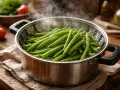 Judías verdes frescas y vibrantes humeando en una vaporera de metal, listas para ser parte de una comida saludable.