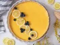 Tarta de limón al horno, decorada con rodajas de limón y arándanos. Un postre refrescante y vibrante.