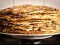 Montón de deliciosos pancakes sin gluten, dorados y esponjosos, apilados en un plato blanco.