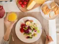 Persona disfrutando una ensalada, tomates, patata asada y un vaso de zumo, parte de su dieta intermitente 16/8.