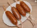 Cuatro chorizos veganos envueltos en plástico transparente, listos para cocinar.