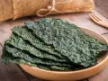 Plato de madera con finas láminas de varios tipos de algas comestibles, listas para disfrutar.