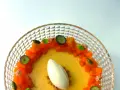 Delicioso flan de mango con helado de vainilla, trozos de mango fresco, arándanos y hojas de menta en un plato de cristal.