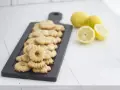 Deliciosas galletas de limón dispuestas en una tabla negra, con limones frescos al lado.