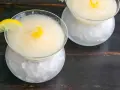 Dos copas de sorbete de limón, una con rodaja de limón y rizo de piel, servidas sobre hielo picado.
