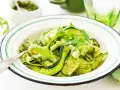Deliciosa ensalada de calabacín en espiral con pesto y rúcula, adornada con piñones. Un plato fresco y vibrante.