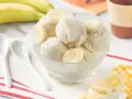 Delicioso helado de platano casero, cremoso y refrescante, servido en un cuenco de cristal con rodajas de plátano fresco.