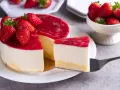 Deliciosa tarta de queso con frutos rojos, cubierta con una capa brillante de mermelada de fresa y decorada con fresas frescas.
