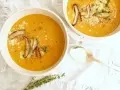 Dos tazones de cremosa sopa de calabaza, adornados con champiñones y queso rallado, listos para ser disfrutados.