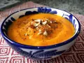 Crema de zanahoria y jengibre, servida en un cuenco azul y blanco, adornada con nueces y pimienta.