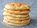 Una pila de pan nube, esponjosos y dorados, parecen nubes comestibles listas para ser disfrutadas.