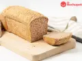 Pan sin gluten recién horneado, con una rebanada lista para disfrutar. Su textura porosa y corteza dorada invitan a probarlo.