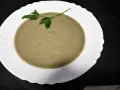 Crema de berenjena suave y sedosa, decorada con una ramita de perejil fresco, lista para disfrutar.
