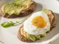 Tostas de aguacate para cenar, una con huevo frito y la otra con rúcula. Delicioso y saludable.