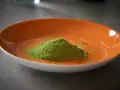 Montículo de polvo verde vibrante, polvo de moringa, en un plato naranja brillante.
