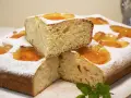 Deliciosa coca de albaricoque, cubierta de azúcar glas y decorada con trozos de fruta. Un trozo apilado revela su esponjosa miga.