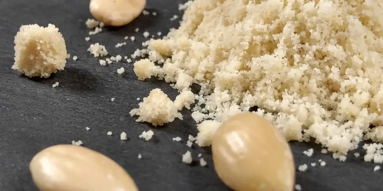 Montón de harina de almendras y almendras enteras. Aprende como hacer harina de almendras casera.