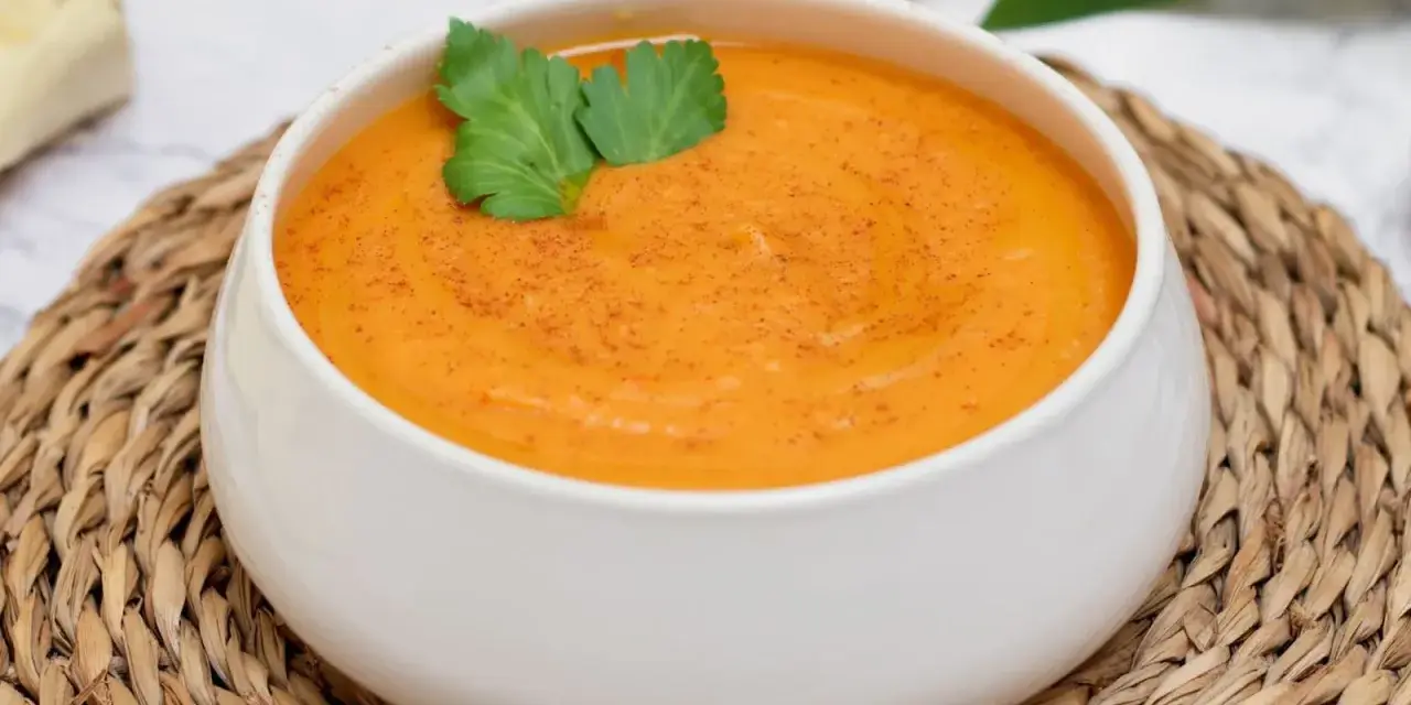 Crema de batata cremosa y reconfortante, espolvoreada con pimentón y decorada con perejil fresco.