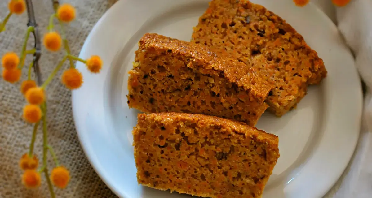 Rebanadas de bizcocho de zanahoria saludable, con trocitos de zanahoria visibles, servidas en un plato blanco.