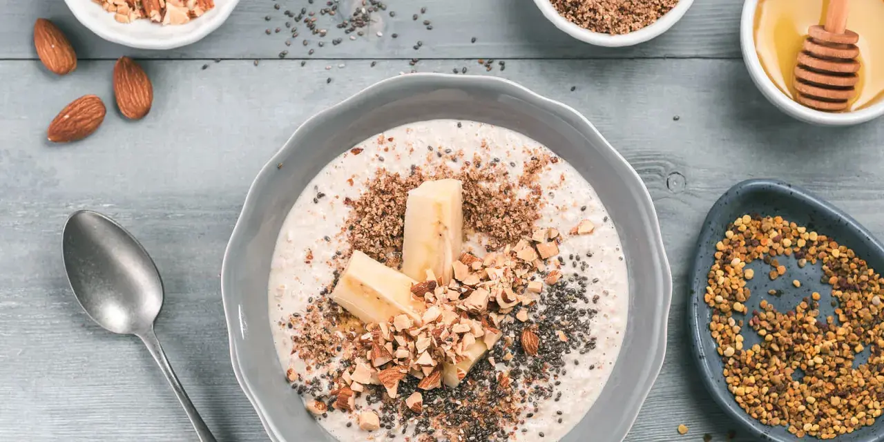 Un tazón de avena con plátano, almendras picadas, semillas de chía y miel. ¡Así es que es la avena, un desayuno nutritivo!