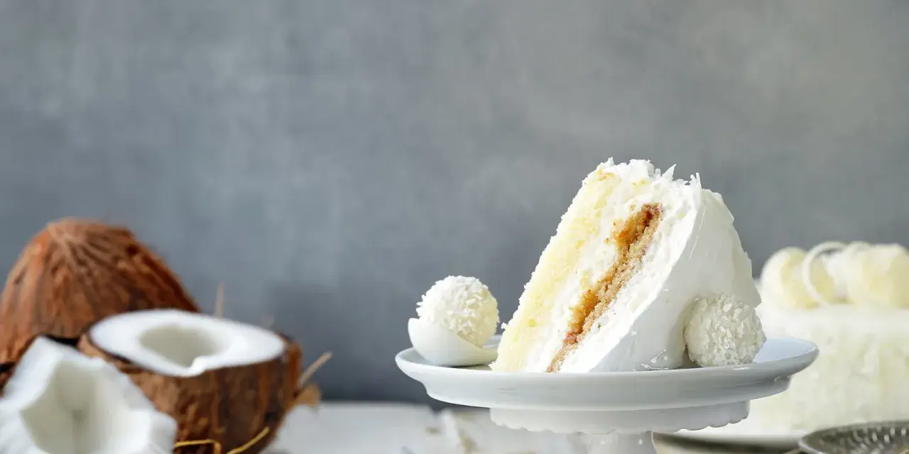 Deliciosa tarta de coco, ideal para tus recetas con harina de coco. Un trozo cremoso con coco rallado y un bombón a juego.