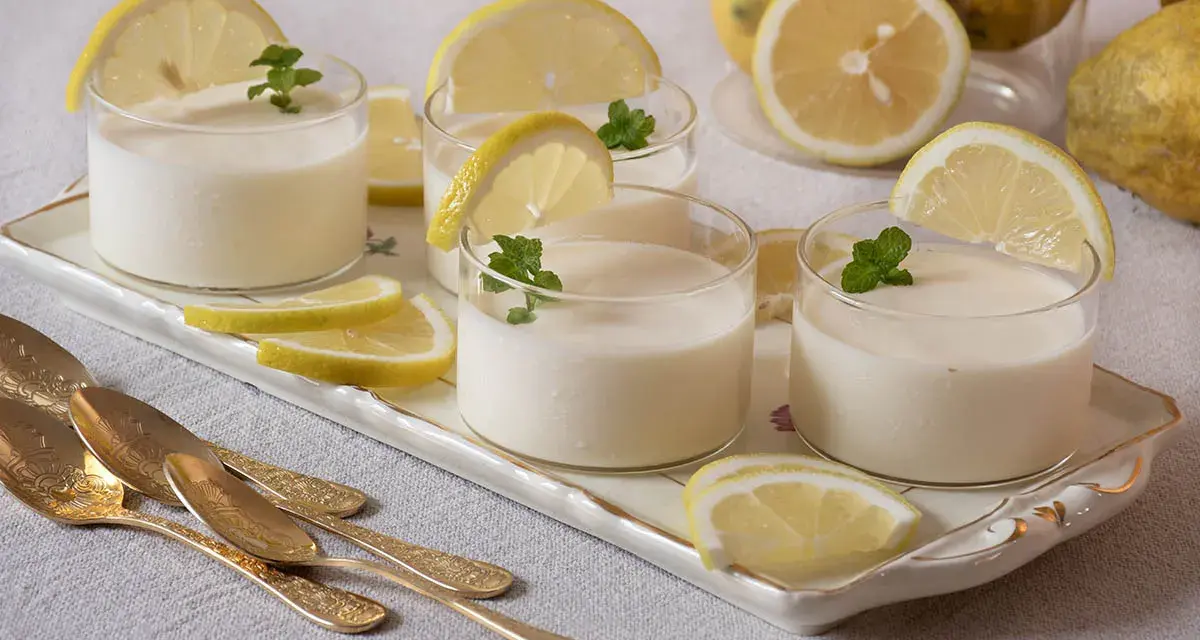 Delicioso postre de lemon curd receta original, servido en vasos con rodajas de limón y menta.