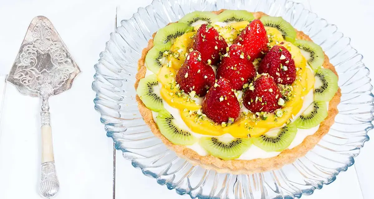 Tarta de frutas con fresas, kiwi y mango, decorada con pistachos. ¡Una delicia visual y gustativa!