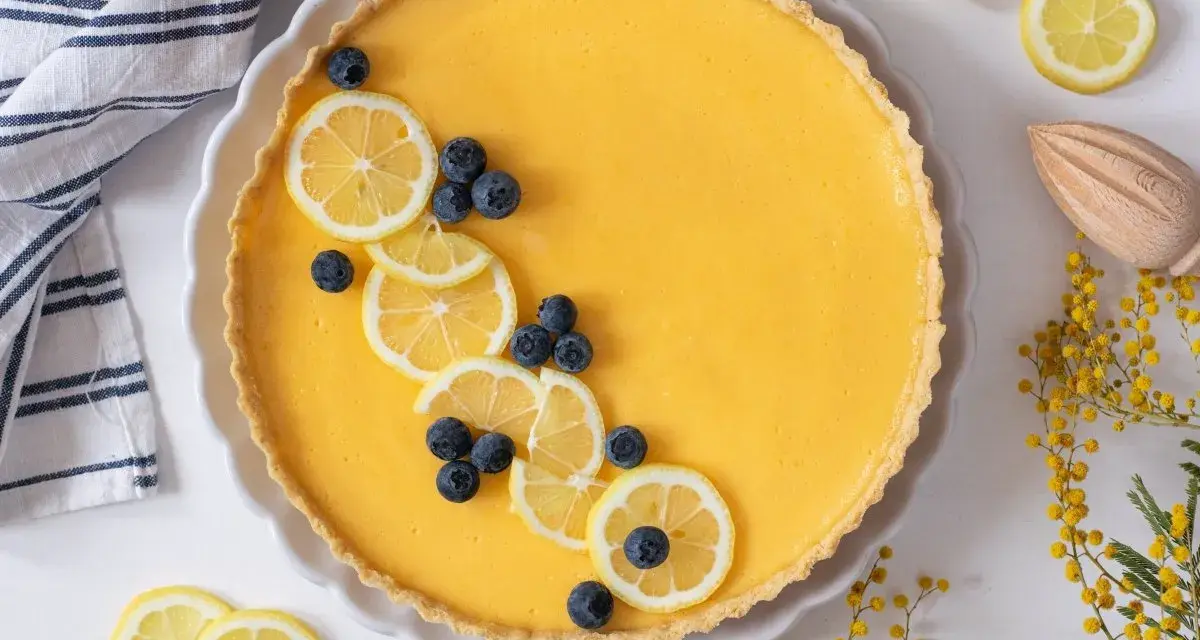 Tarta de limón al horno, decorada con rodajas de limón y arándanos. Un postre refrescante y vibrante.
