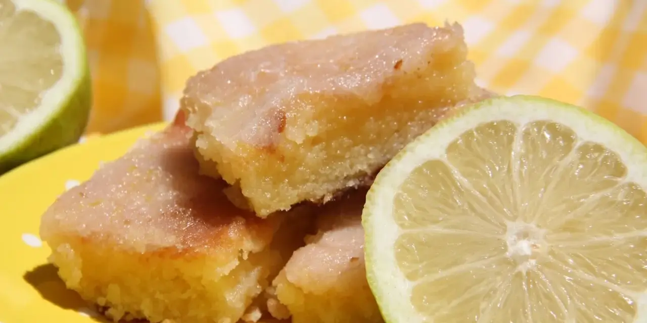 Deliciosos trozos de brownie de limón con glaseado brillante y rodajas de limón fresco.