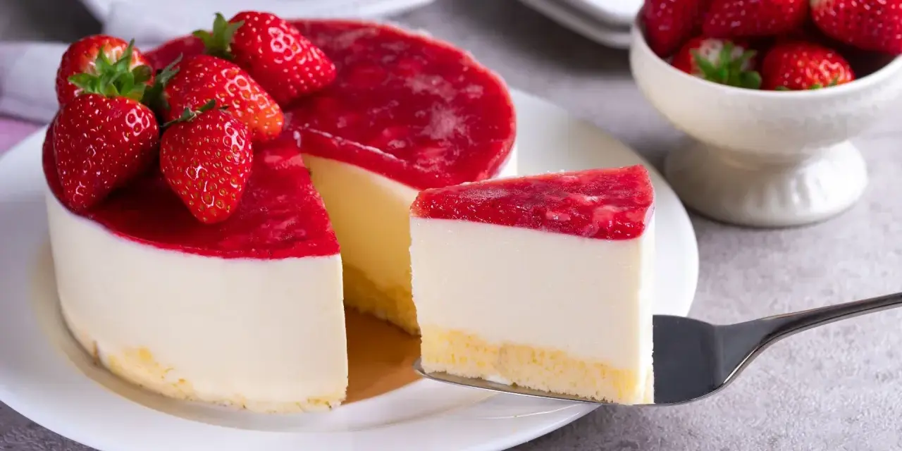 Deliciosa tarta de queso con frutos rojos, cubierta con una capa brillante de mermelada de fresa y decorada con fresas frescas.