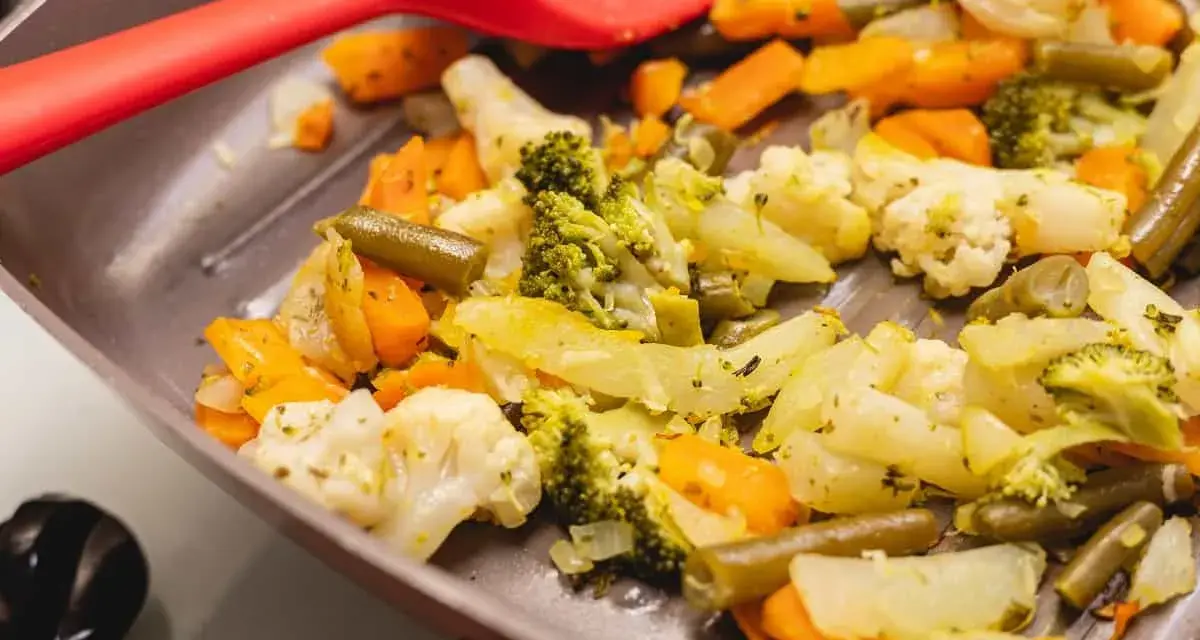 Coliflor al ajillo salteada con brócoli, zanahoria y judías verdes en una sartén, lista para servir.