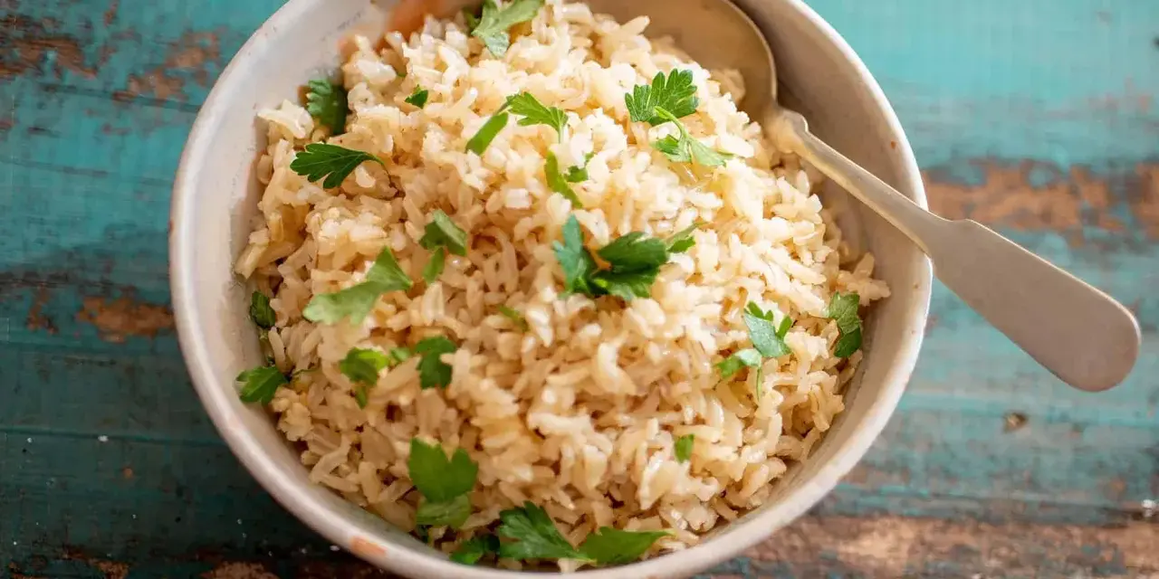 Un tazón de arroz integral esponjoso, adornado con perejil fresco, listo para ser disfrutado.