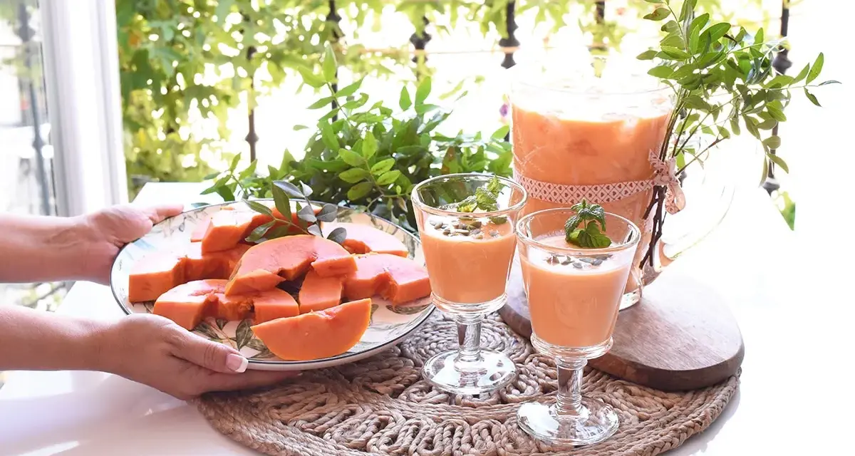 Delicioso zumo de papaya servido en copas y jarra, acompañado de papaya fresca en rodajas.