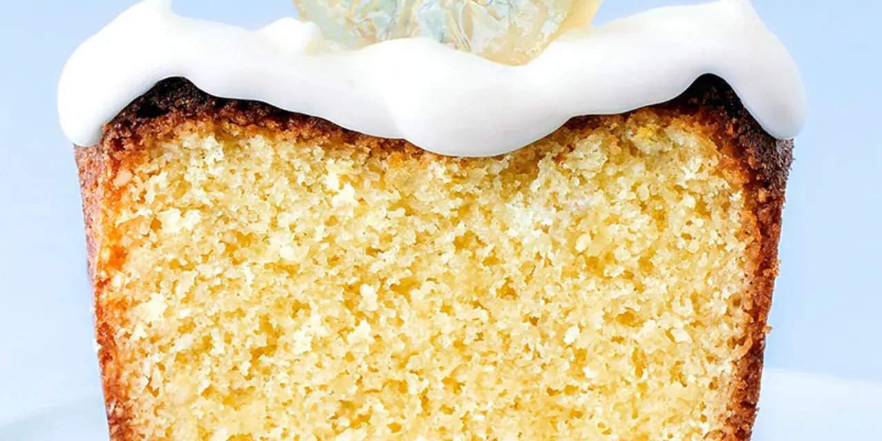 Rebanada de bizcocho esponjoso con un delicioso frosting de limón y una rodaja de limón cristalizado encima.
