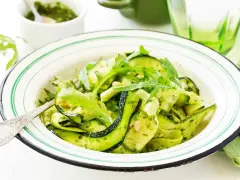 Deliciosa ensalada de calabacín en espiral con pesto y rúcula, adornada con piñones. Un plato fresco y vibrante.