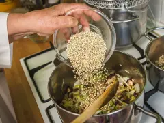 Mano añade trigo sarraceno a una olla con verduras y champiñones.