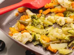Coliflor al ajillo salteada con brócoli, zanahoria y judías verdes en una sartén, lista para servir.