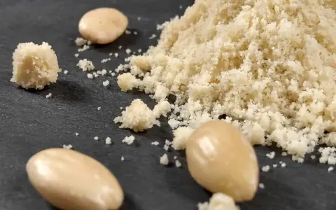 Montón de harina de almendras y almendras enteras. Aprende como hacer harina de almendras casera.