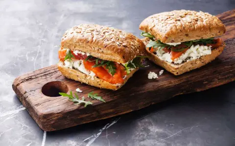 Dos sándwiches de salmón y queso fresco en pan integral, perfectos para un menú de ayuno intermitente.