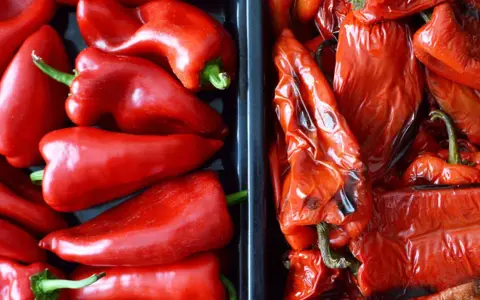 Dos recipientes llenos de pimientos rojos, unos frescos y brillantes, otros pimientos asados con la piel arrugada y un toque tostado.
