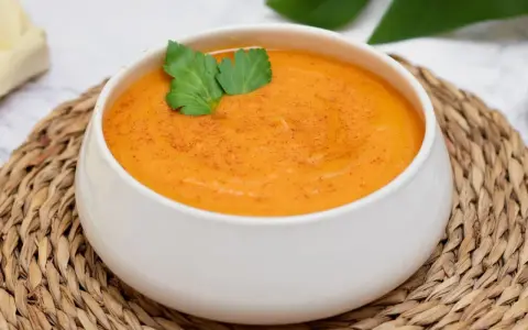 Crema de batata cremosa y reconfortante, espolvoreada con pimentón y decorada con perejil fresco.
